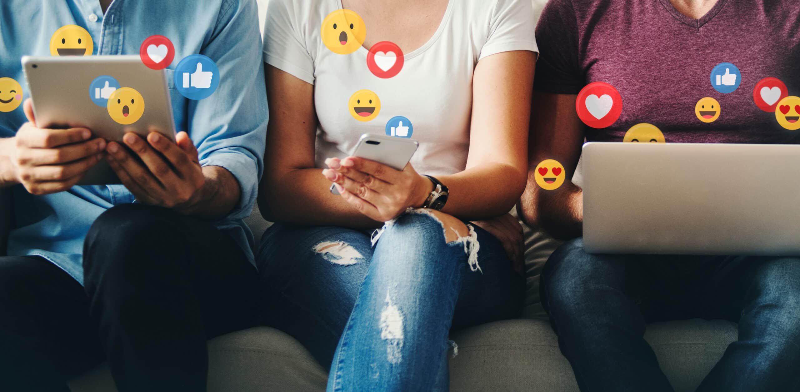 3 Personen sitzen nebeneinander mit Tablet, Smartphone und Laptop, während Social-Media-Symbole wie Likes, Herzen und Emojis symbolisch um sie herum schweben.